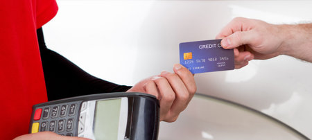 Gas station staff receive blue credit card (mock up) from car owner's hand. Close up