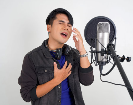 Young asian man with headphones  singing with microphone. Portrait on white background with studio...