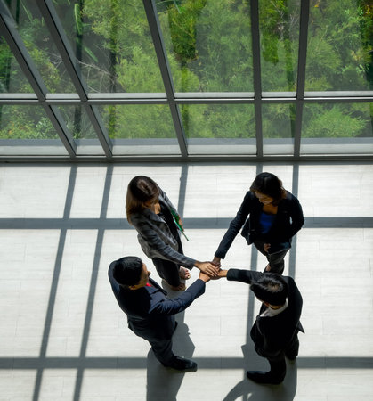 Business partners join hands in the modern office. Standing near the window while the sunlight...