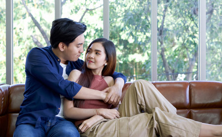 Young lovers spend time together on holidays in the living room. Both make eye contact while the man...