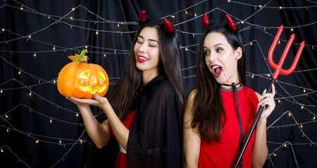 Young russian woman with pumpkin carved into a face enjoy halloween party decorated with flashing lights with her mexican friend.の写真素材