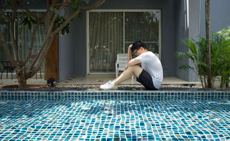 Asian man in white T-shirt sitting  in front of a resort room after a morning workout. Health care activities during the holidaysの写真素材
