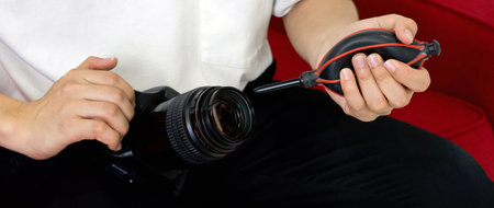 Young photographer cleaning the camera and lens with a air blower camera cleaning after shooting fashion models in the studio.の写真素材
