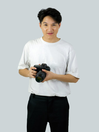 Asian photographer holding DSLR camera with both hand while standing in a white photography scene....