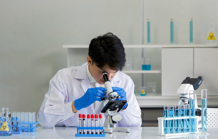 Young asia scientist using a microscope to see the patient's blood. Coronavirus disease 2019...