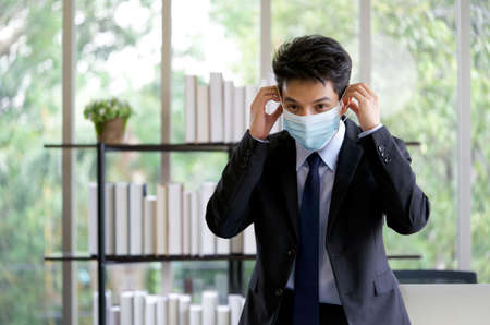Asian businessman in a suit wearing face mask before beginning the presentation in the meeting. Concept of new normal office business during  pandemic outbreak.の写真素材