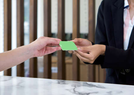 The hotel manager in the suit handed a room card to the guest. Close upの写真素材