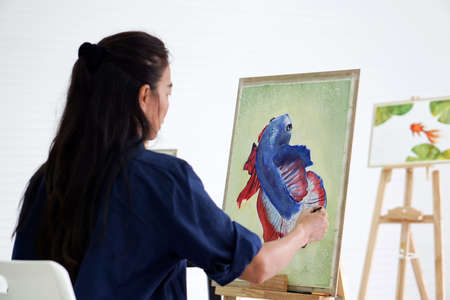 Asian woman drawing a betta fighting fish on white board in watercolor painting art classesの写真素材