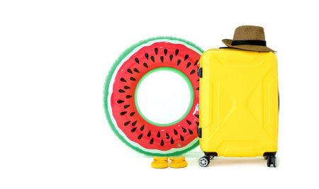 Summer travel concept. Colorful inflatable balls, sandals, yellow suitcase and straw hat with a...