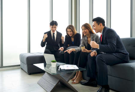 Group of business people in suit looking at report excited by good news with smiling expressions.の写真素材