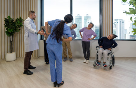 Caucasian doctor in white gown and young asian physical therapist in blue uniform leads the elderly...