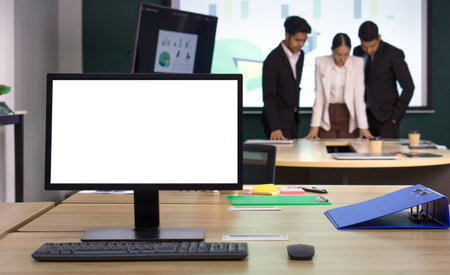 Blank screen desktop pc computer monitor on the desk. Business partners meeting in the background. Working atmosphere in a modern officeの写真素材