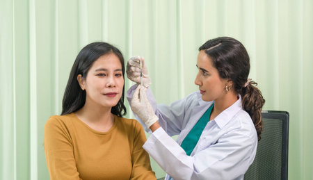 Doctor in white gown and protective glove prepares to give an injection to a female patient.