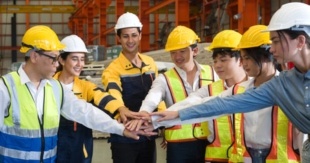 Group of male and female factory labor join hands together after finish meeting. Everyone wearing...
