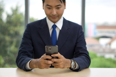 Businessman in suit and tie typing text message on mobile phone.の写真素材
