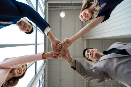Team building concept. Coworker standing in circle bumping fist together, celebrating business...