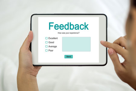 A focused woman is using her tablet computer, displaying the screen with the prominently visible word Feedback on it.の写真素材