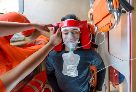 A person is wearing an oxygen mask, getting help from paramedic in orange uniform inside an...