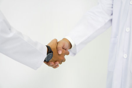 Healthcare professional and scientist in white lab coat shaking hand on white background. Closeupの写真素材