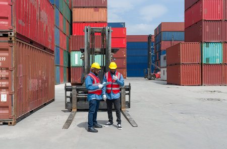 Two shipment worker dressed in hardhat, safety vest and protective glove working during the day...