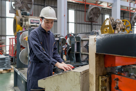 A man in a hardhat and mechanic coverall dust protection suit operate industrial equipment inside a...