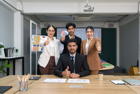 Team of successful business people gather around a table raise finger thumb up with a smile. Concept of leadership.の写真素材