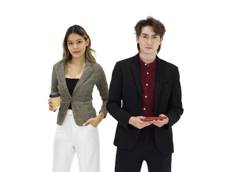 Two business professional pose confidently in a modern studio setting. The woman hold a coffee cup while the man hold tablet computer, illustrating a collaborative work atmosphere.の写真素材