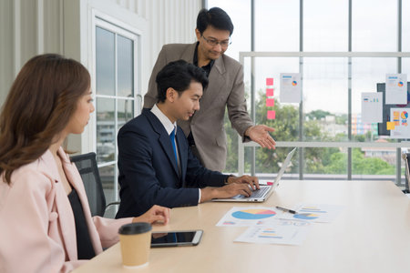 Business professional collaborating with enthusiasm while examining data on a laptop in a...