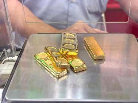 Weighing gold bar at a financial center show several shiny gold piece arranged neatly. The atmosphere is busy, indicating financial transaction occurring nearby.の写真素材