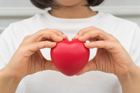 Woman in white shirt holding red love heartの写真素材
