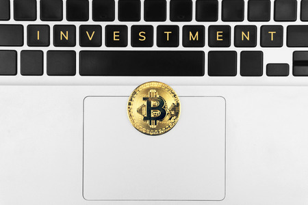 crypto currency mining concept, a bitcoin on the laptop with 'investment' word on keyboard buttonの写真素材