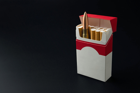 Smoking kills concept, a gun bullet in the cigarette pack on dark backgroundの写真素材