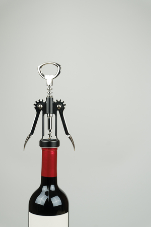 a metal corkscrew with a bottle of red wineの写真素材
