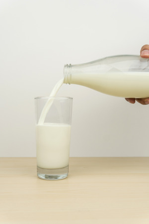 hand pouring milk from the bottle into a glassの写真素材