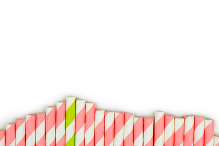 top view of a green striped straw among the pink striped straws on white backgroundの写真素材