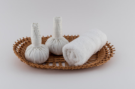 Thai Herbal Massage Balls and Rolled Towel on Wicker Trayの写真素材
