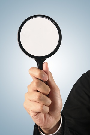 Magnifying glass in hand  on blue background  (path in side)
の写真素材