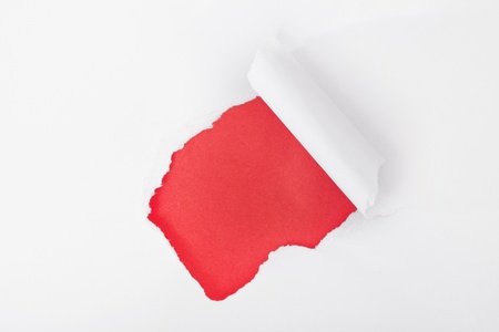 Hole ripped in paper on redの写真素材
