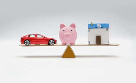 Piggy bank, toy house and car balancing on white background.の写真素材