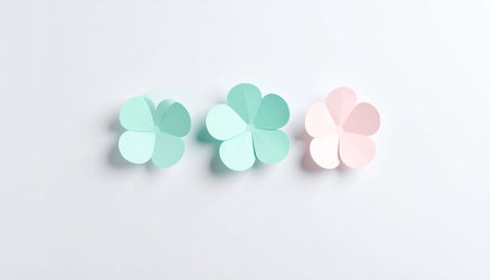 Three pastel paper flowers, teal and pink, arranged horizontally on a light gray background, exhibiting a minimalist aestheticの素材