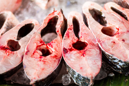 Selective focus in center, pieces of fresh uncooked red fish on banana leaves at Thai rural marketの写真素材