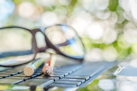 Close up of pencils and eyeglasses on laptop keyboardの写真素材