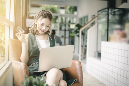 Beautiful Asian woman holding credit card and working on laptop or notebook computer. Online shopping concept.の写真素材