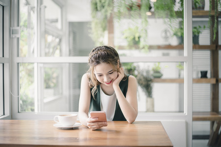 Young beautiful Asain lady touching and browsing her smart phone at home.の写真素材