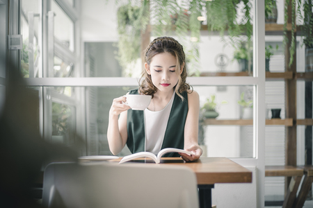 Portrait of Asian woman smiling in coffee shop cafe. Beautiful girl with coffee cup in the morning.の写真素材
