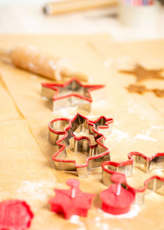 Red ginger bread shapes and dough laying on brown baking paper.の写真素材
