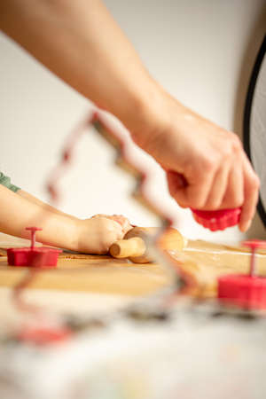 Young woman prepares gingerbread for Christmas, Pushes gingerbread shapes in dough on brown baking paper.の写真素材
