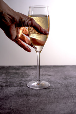 A young woman reaches for a golden glass of champagne.の写真素材