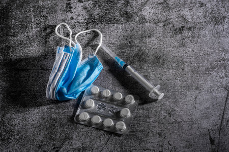 Face mask, syringe, pills on dark background. Medicine and healthcare. Medications and pharmacy.の写真素材