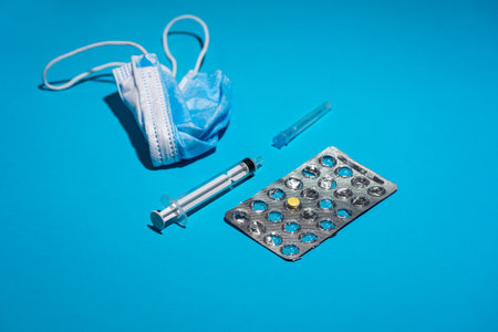 Blue face mask, pills, syringe on blue background. Medicine and healthcare. Medications and pharmacy.の写真素材